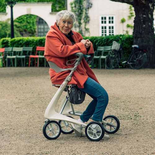 Rollator Carbo Ultralight beige avec femme assise dans un parc